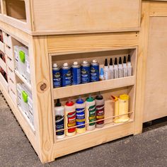 an assortment of paints and glues on display in a store shelf with wooden shelves