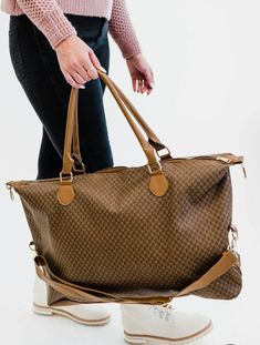 Did someone say must-have bag? The Olivia weekender is an absolute essential in every woman's closet. The timeless patterns, buttery smooth vegan leather, and versatile straps make it a top contender for the title of the perfect bag.Great for travel, carry-on duffle bag, vacation, overnight, extended weekend getawaysand day trips. Details: The Olivia is 26" wide x 15" long x 7" deep detachable strap adjusts to be up to 42" long Gold hardware 3 interior pockets, including 1 with a zipper Brown Weekender Bag With Adjustable Strap For Everyday Use, Trendy Satchel Weekender Bag With Adjustable Strap, Versatile Brown Travel Bag For Weekend Trips, Classic Brown Travel Bag With Adjustable Strap, Brown Classic Travel Bag With Adjustable Strap, Brown Rectangular Travel Bag With Adjustable Strap, Brown Large Capacity Weekender Bag For Weekend Trips, Dark Tan Travel Shoulder Bag, Classic Brown Duffle Bag With Adjustable Strap