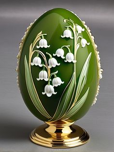 an egg decorated with lily of the valley flowers on a gold base, sitting on a gray surface