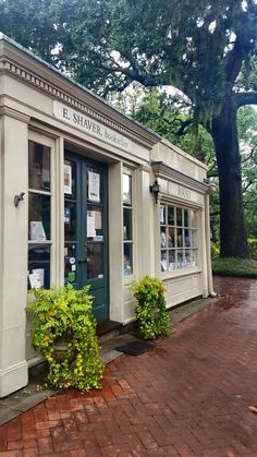 an old building with many books on the front and side windows, along with green plants