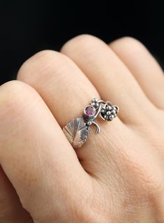 a woman's hand holding a ring with an elephant and leaves design on it