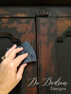 a person is wiping up some wood with a cloth on top of the cabinet door