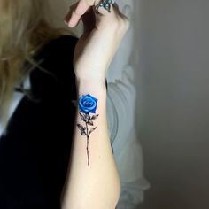 a woman with a blue rose tattoo on her arm