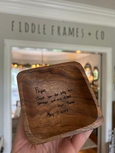 someone holding up a wooden plaque with writing on it