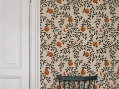 a chair sitting in front of a wallpaper with oranges on it