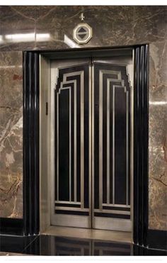 an elevator with marble walls and black doors