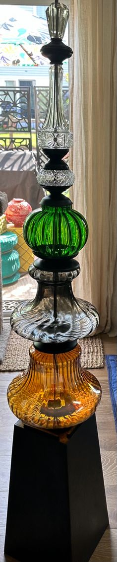 a multi - colored glass vase sitting on top of a wooden table next to a window