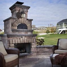 two wicker chairs sitting in front of an outdoor fireplace