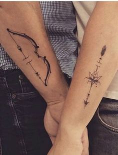 two people holding hands with tattoos on their arms