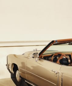 the interior of a convertible car parked in front of a white wall with wood trim