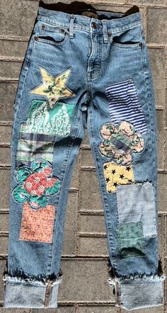 an old pair of jeans with patches and flowers on them sitting against a brick wall