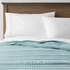 an unmade bed with white pillows and blue quilted bedspread on it