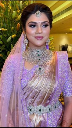 a woman in a purple sari with jewelry on her neck and headpieces