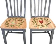 two wooden chairs with painted designs on the back and sides, one has a heart