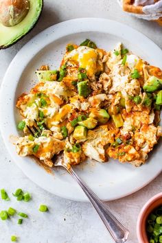 a white plate topped with food next to an avocado