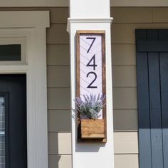 a house number sign mounted to the side of a building with a planter in it