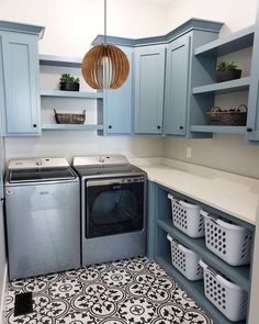 a washer and dryer in a laundry room with blue cabinets, patterned floor tiles