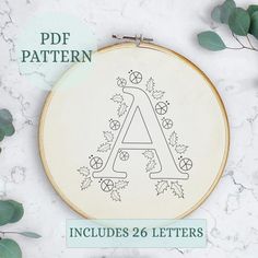 an embroidery pattern with the letter a in it and leaves around it on a marble surface