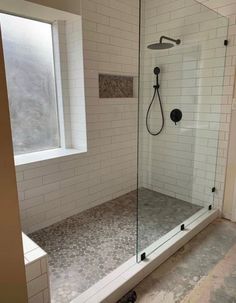 a walk in shower sitting next to a window on top of a tiled flooring