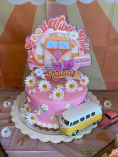 there is a pink cake with flowers on it and a bus in the back ground