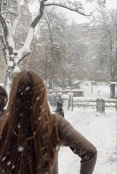 a woman standing in the snow with her back to the camera