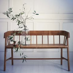 a wooden bench sitting next to a plant in a vase on top of it's back