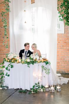 a bride and groom sitting at a table with candles