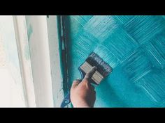 a person is painting a wall with blue paint and a brush in their hand,