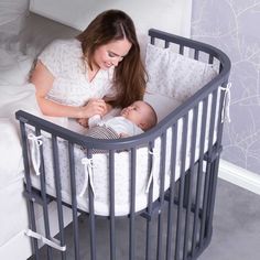 a woman laying in her crib with a baby sleeping next to her on the bed