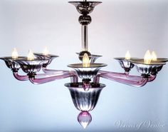 a chandelier with five lights hanging from it's sides and four candles in the middle