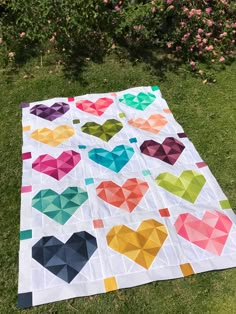 a colorful quilt on the grass with hearts