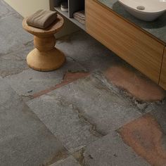 a bathroom with stone flooring and a sink on the counter next to a wooden cabinet