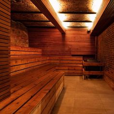 a wooden bench sitting in the middle of a room with brick walls and beams above it