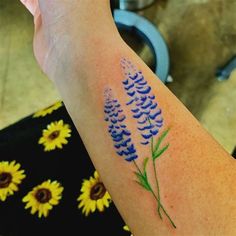 a person with a tattoo on their arm has a blue flower in the foreground