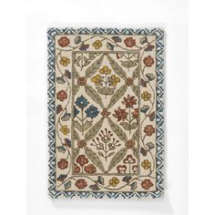 an embroidered wall hanging with flowers and leaves on the front, in blue and beige colors