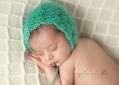 a newborn baby wearing a green crochet hat