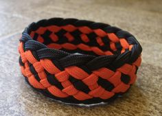 an orange and black braided bracelet sitting on top of a counter