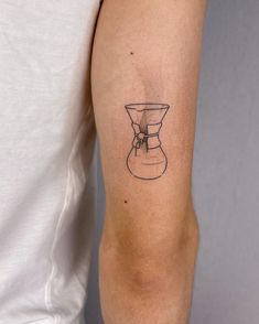 a tattoo on the arm of a man with a coffee pot in front of him