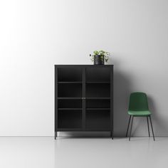 a green chair sitting next to a black bookcase on top of a white floor