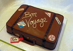 a cake shaped like a suitcase with bon voyage written on the side and stickers attached to it