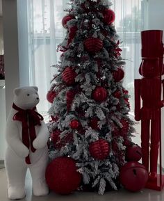 a christmas tree decorated with red and silver ornaments next to a white teddy bear in front of it