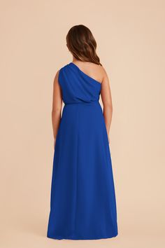 a woman in a blue dress with one shoulder draped over her shoulders, looking down at the