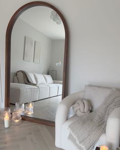 a living room with a couch, mirror and candles on the floor in front of it