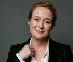 a woman in a black jacket and white shirt is posing for a photo with her hand on her tie