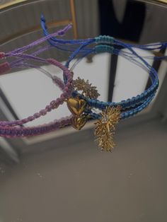 two bracelets with charms hanging from them on a mirror surface in front of a window