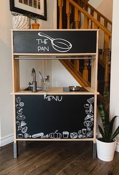 a black and white chalkboard with the words the pan on it next to a potted plant