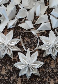 several white origami flowers on a black and brown tablecloth with intricate designs