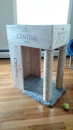 a cat house made out of wood and rope with a ball on the floor next to it