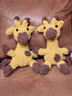 two stuffed giraffes sitting on top of a brown leather couch next to each other