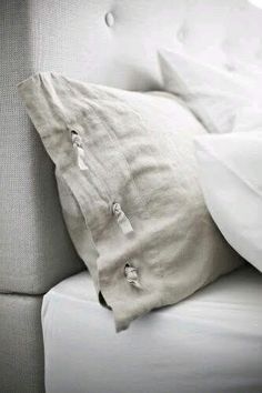 a white couch with two pillows on top of it's back and one pillow that has been turned down